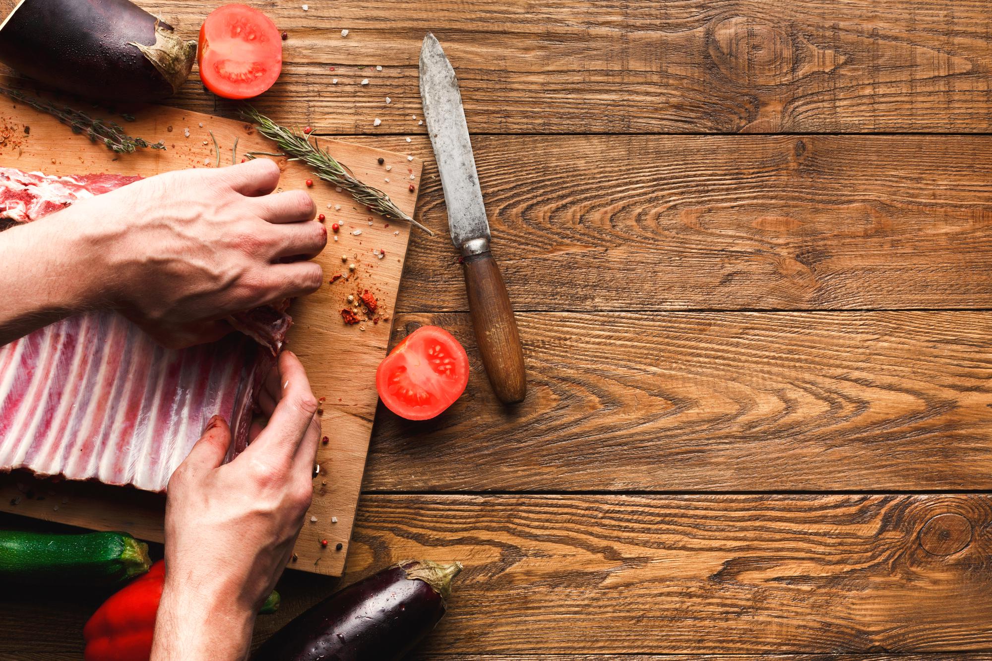 Chef insegna tecnica di taglio su banco di legno